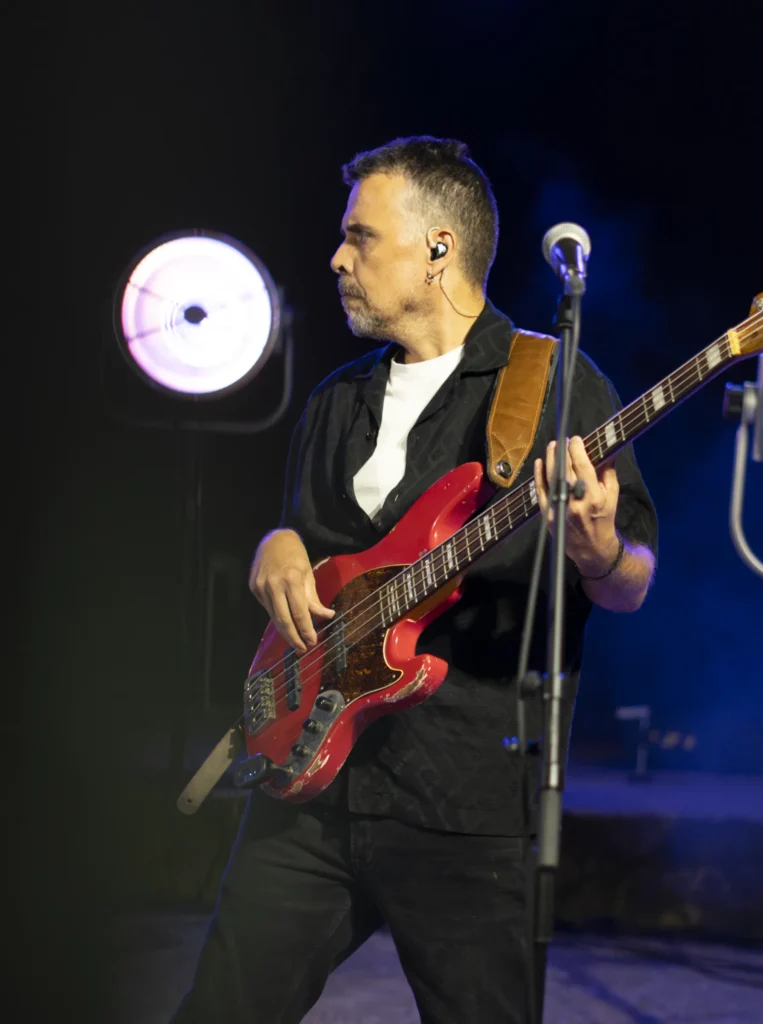Baixista cun baixo vermello toca no escenario iluminado durante o concerto nocturno da festa