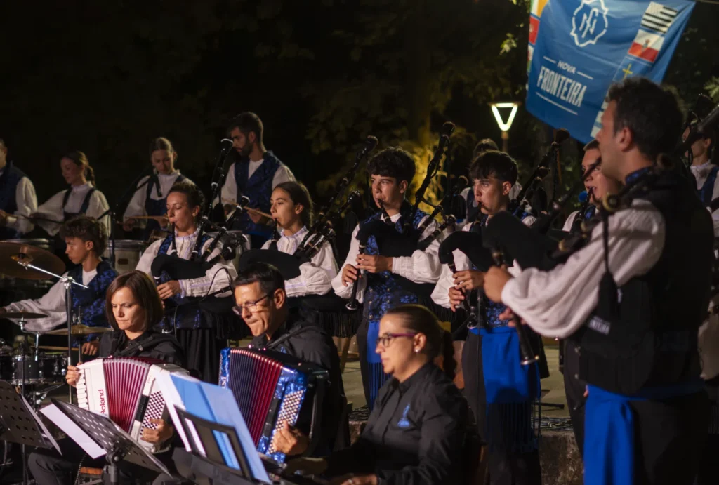 Banda de gaitas con chalecos azuis e acordeóns actuando de noite na Festa do Pemento
