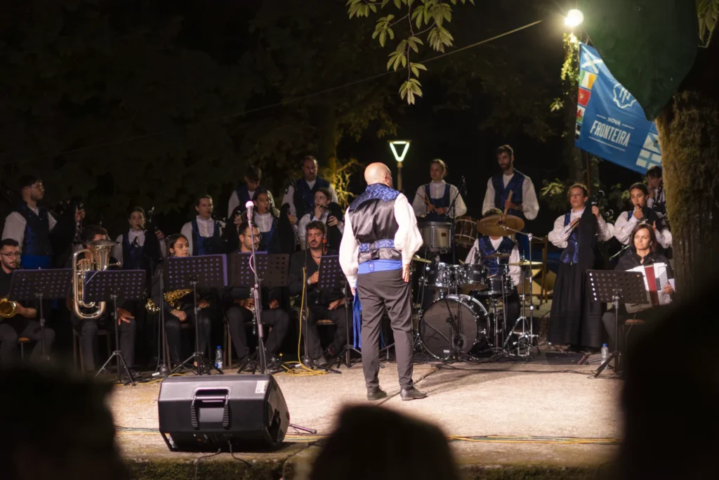 Banda de gaitas actuando de noite co director de costas diante do público da festa