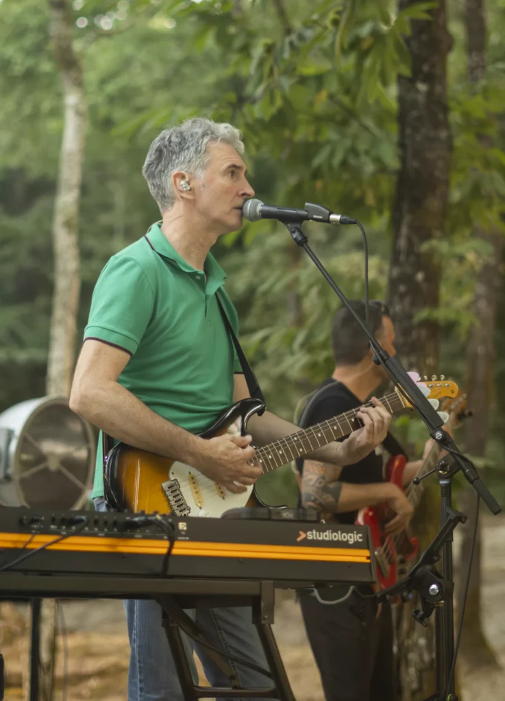 Cantante con guitarra eléctrica actúa ao aire libre entre os carballos do recinto da festa
