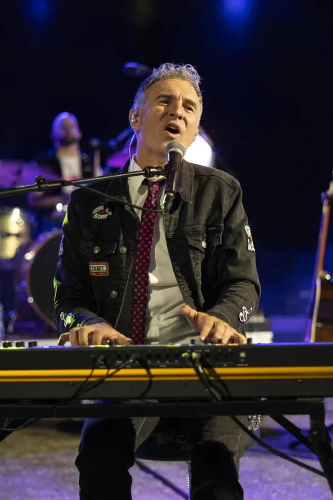 Cantante tocando o teclado e cantando baixo as luces azuis do concerto nocturno