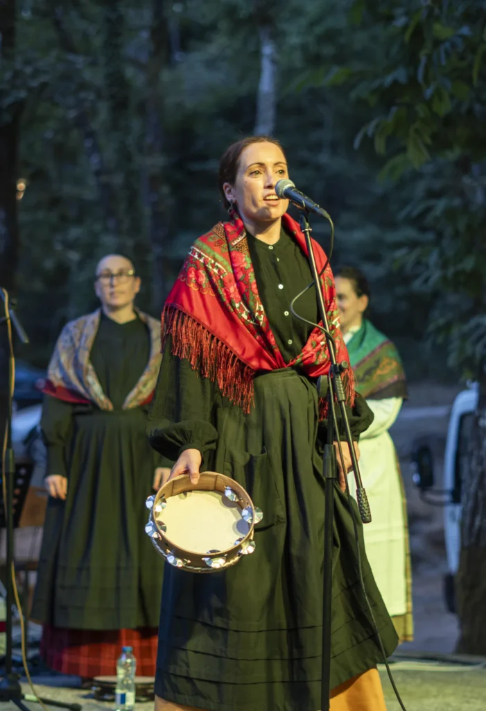 Cantareira con mantón vermello cantando ao micrófono mentres toca a pandeireta ao solpor