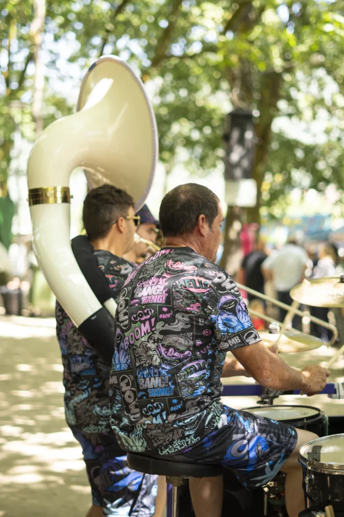 Percusionista e sousafonista da charanga tocando de costas baixo os carballos do recinto