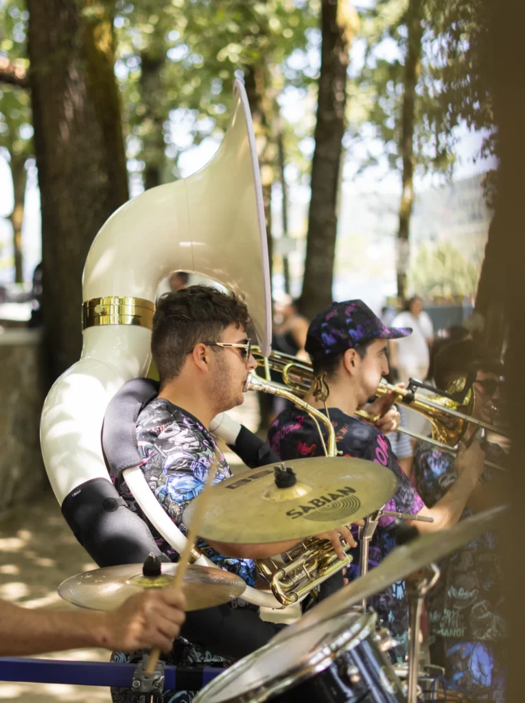 Charanga tocando ao aire libre con sousáfono, trombón e batería entre as árbores do campo