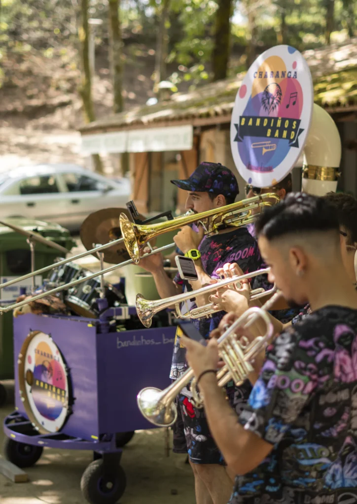 Músicos dunha charanga tocando trombón e trompetas polos camiños da Festa do Pemento