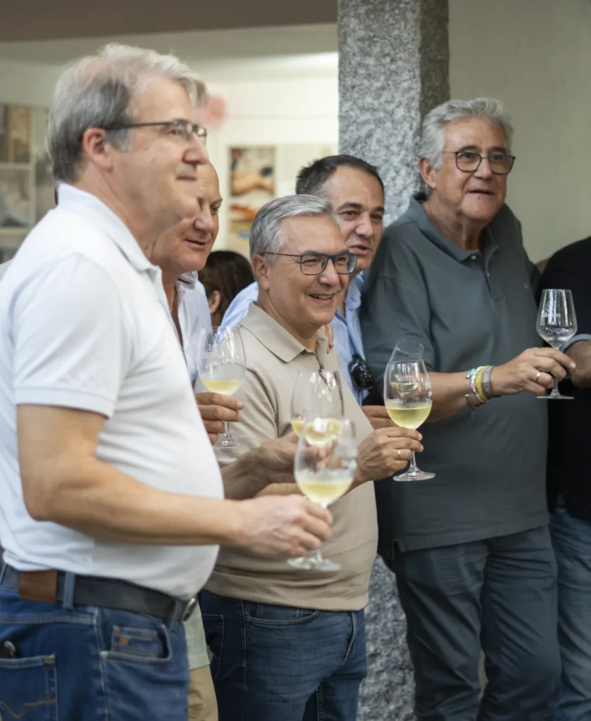 Grupo de homes conversando e sorrindo con copas de viño branco na Festa do Pemento