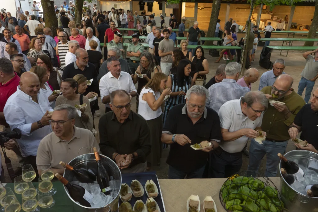 Vista elevada do público degustando pementos fritos e viño branco no recinto da festa