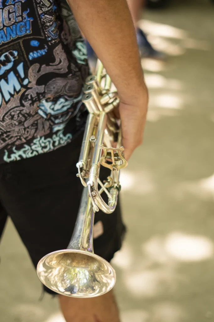 Detalle das mans dun trompetista suxeitando o instrumento antes de tocar no recinto da festa
