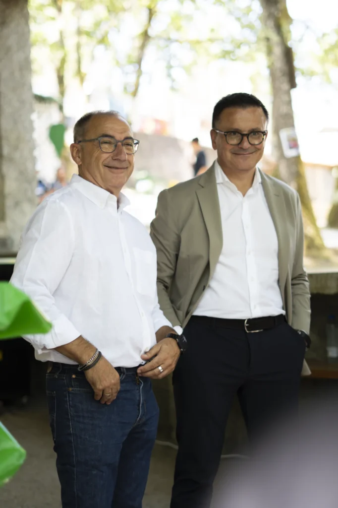 Dous homes posan sorrindo baixo as árbores do campo da Festa do Pemento