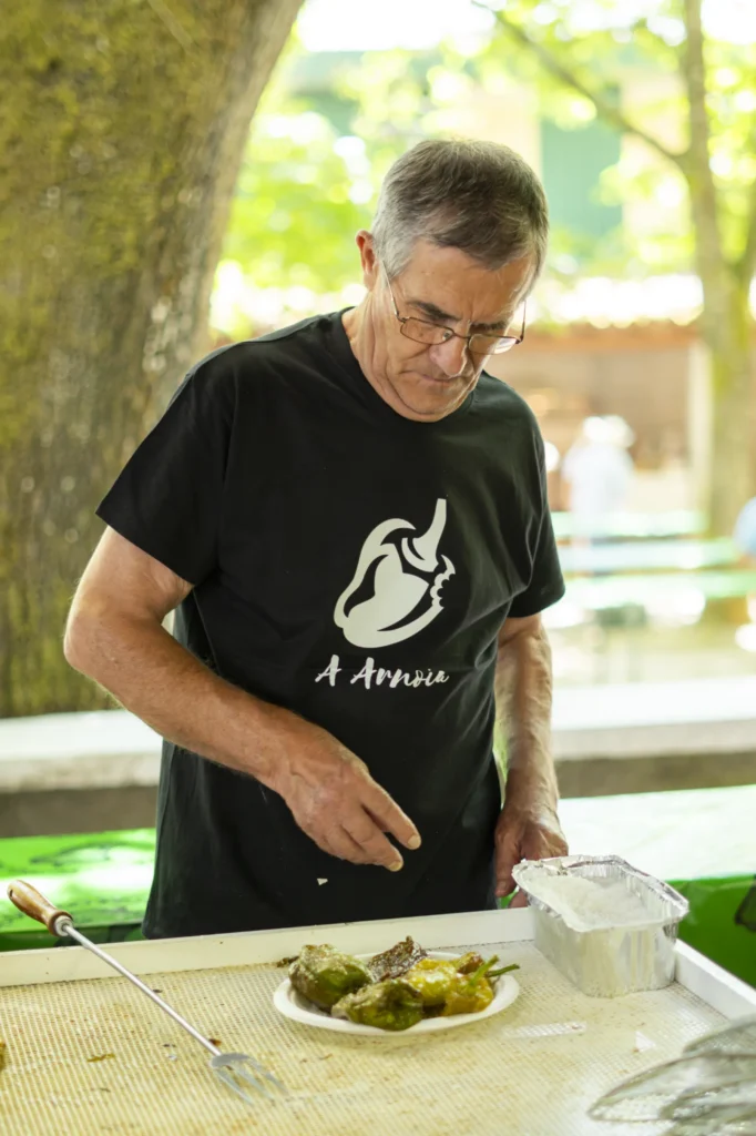 Home cunha camiseta do pemento de A Arnoia prepara un prato de pementos fritos