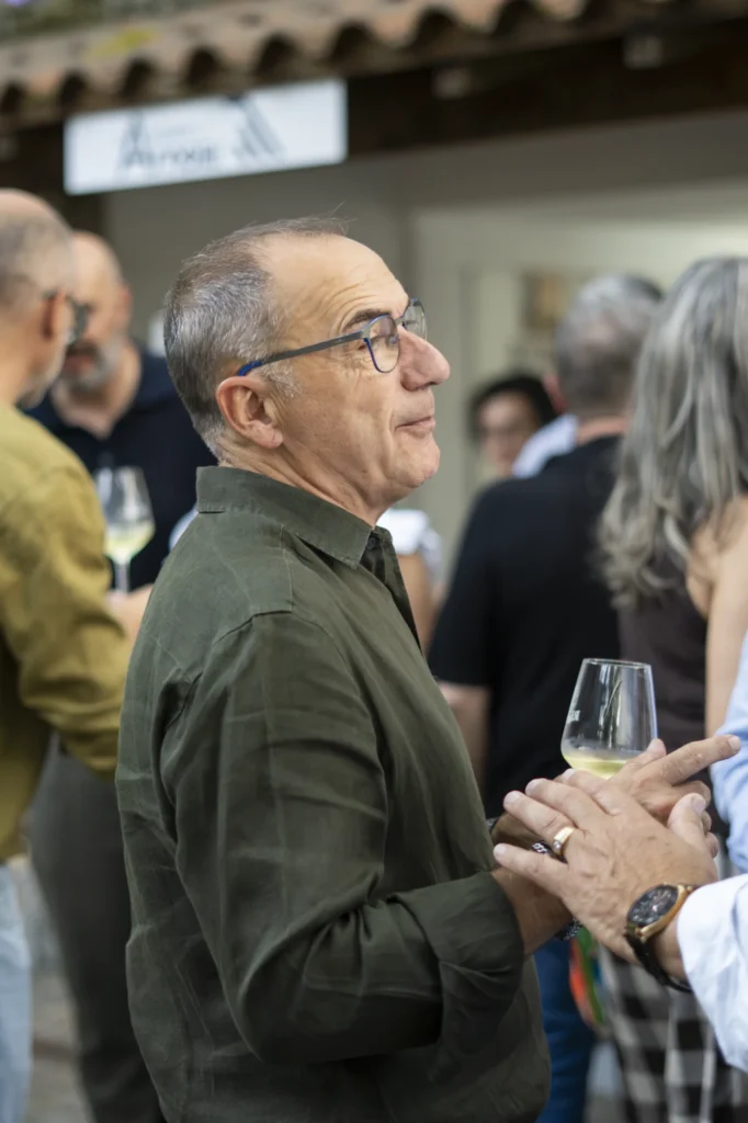 Home con lentes e copa de viño branco conversa nunha recepción da Festa do Pemento
