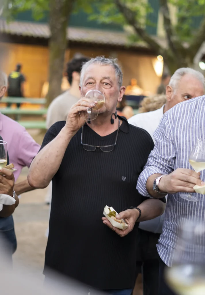 Home bebendo viño branco cunha tapa de pementos asados na man durante a degustación