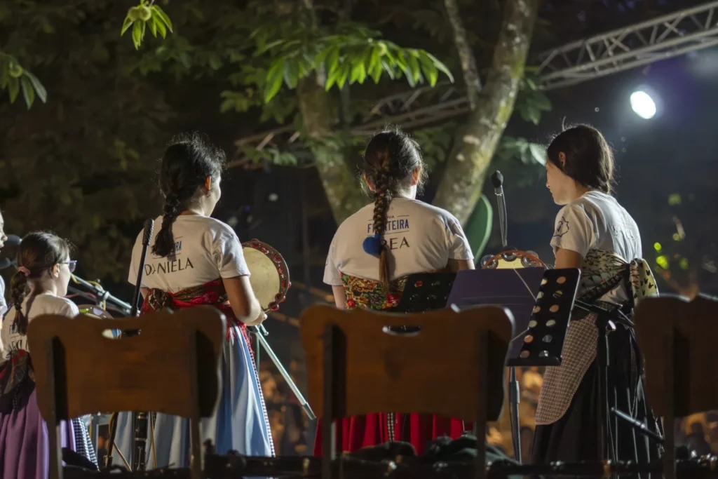 Nenas cos mandís tradicionais e pandeiretas de costas durante a actuación nocturna no escenario