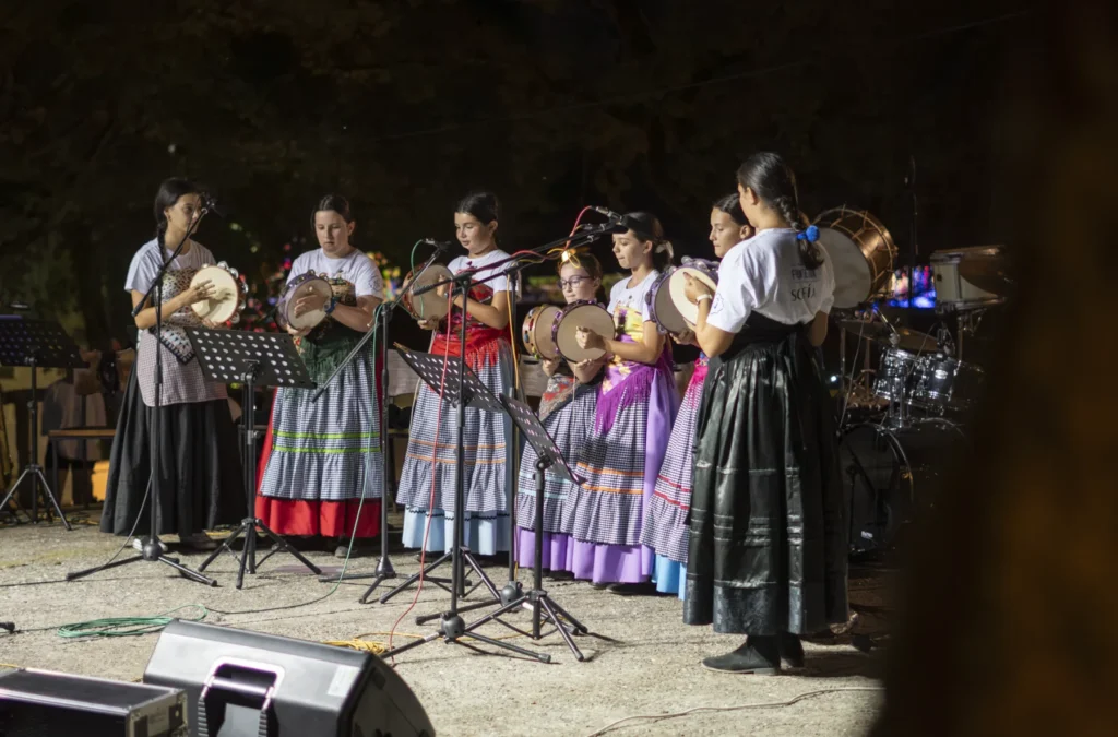 Nenas con saias tradicionais tocan pandeiretas durante a actuación nocturna na Festa do Pemento