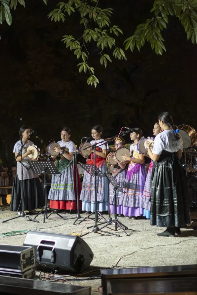 Nenas pandereteiras cantando de noite no escenario ao aire libre da Festa do Pemento