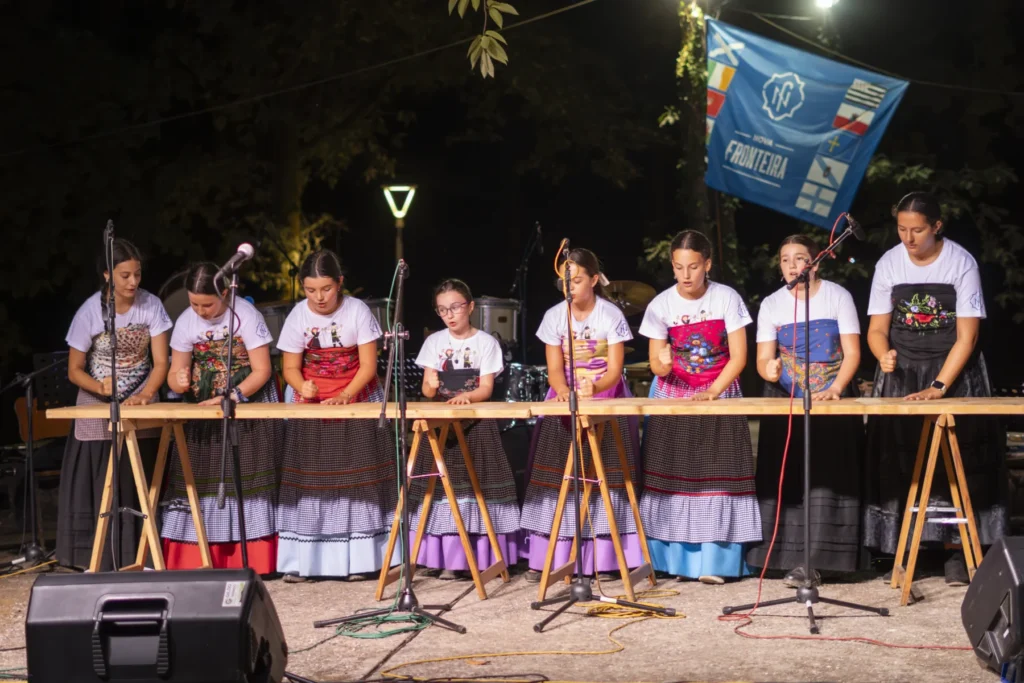 Nenas con traxe tradicional percuten sobre unha táboa de madeira no escenario da festa