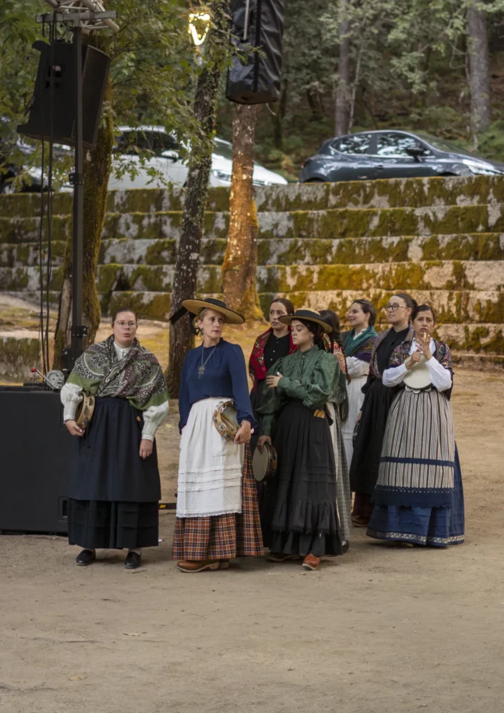 Pandeireteiras con traxe tradicional galego agardando a súa quenda diante do muro de pedra