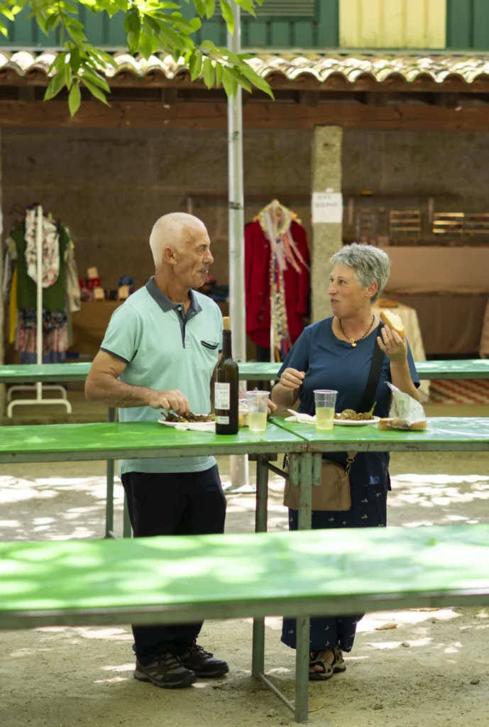 Parella conversando de pé mentres comparte un prato de pementos e unha botella de viño