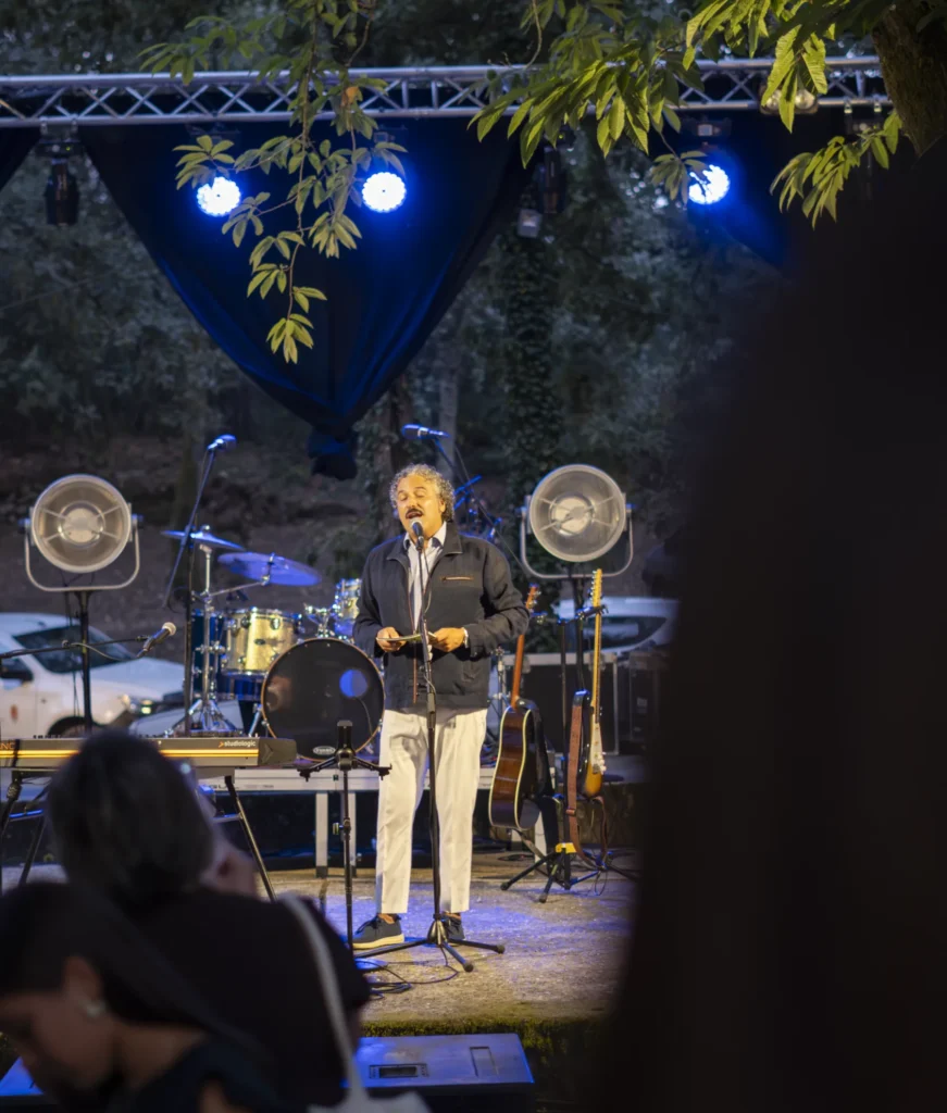 Presentador le ante o micrófono no escenario nocturno iluminado por focos azuis