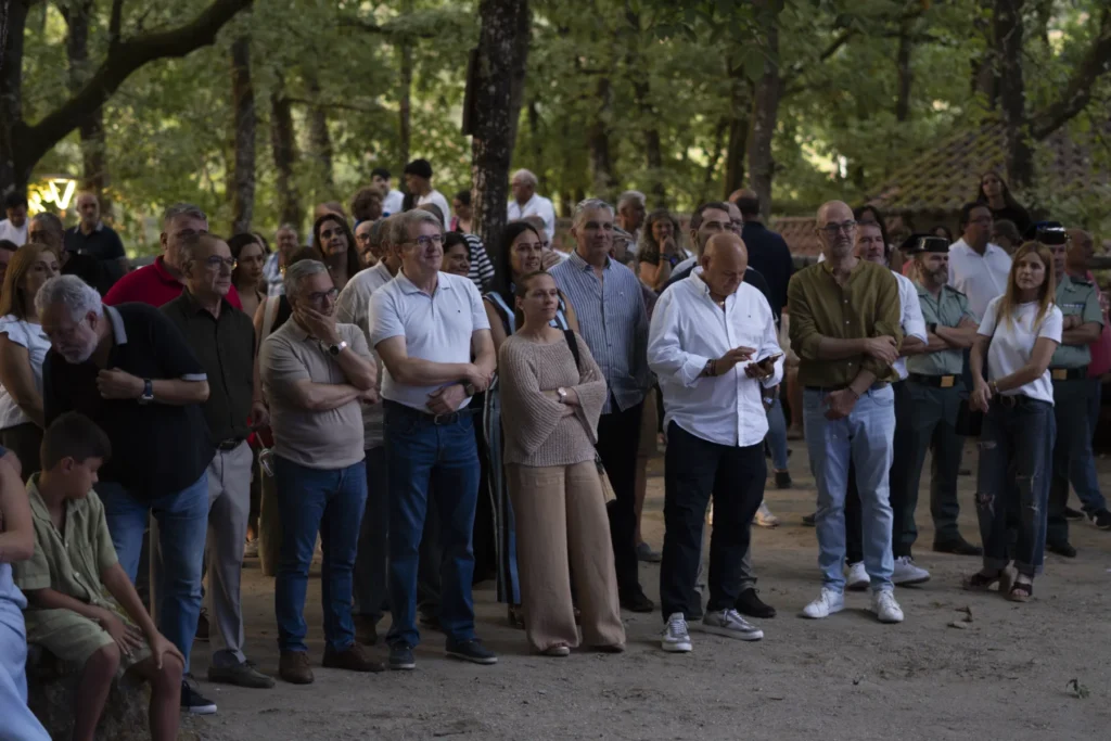 Público numeroso de pé baixo os carballos seguindo un acto da Festa do Pemento de Arnoia