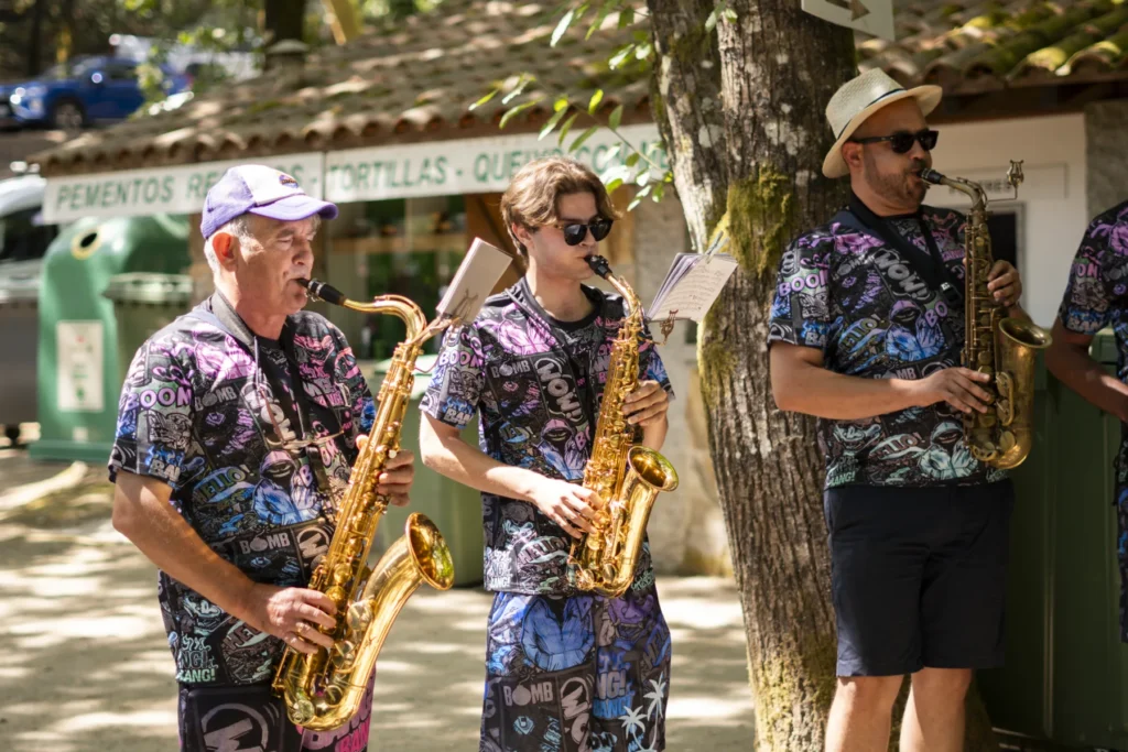 Tres saxofonistas dunha charanga tocando diante dun posto de pementos recheos e tortillas