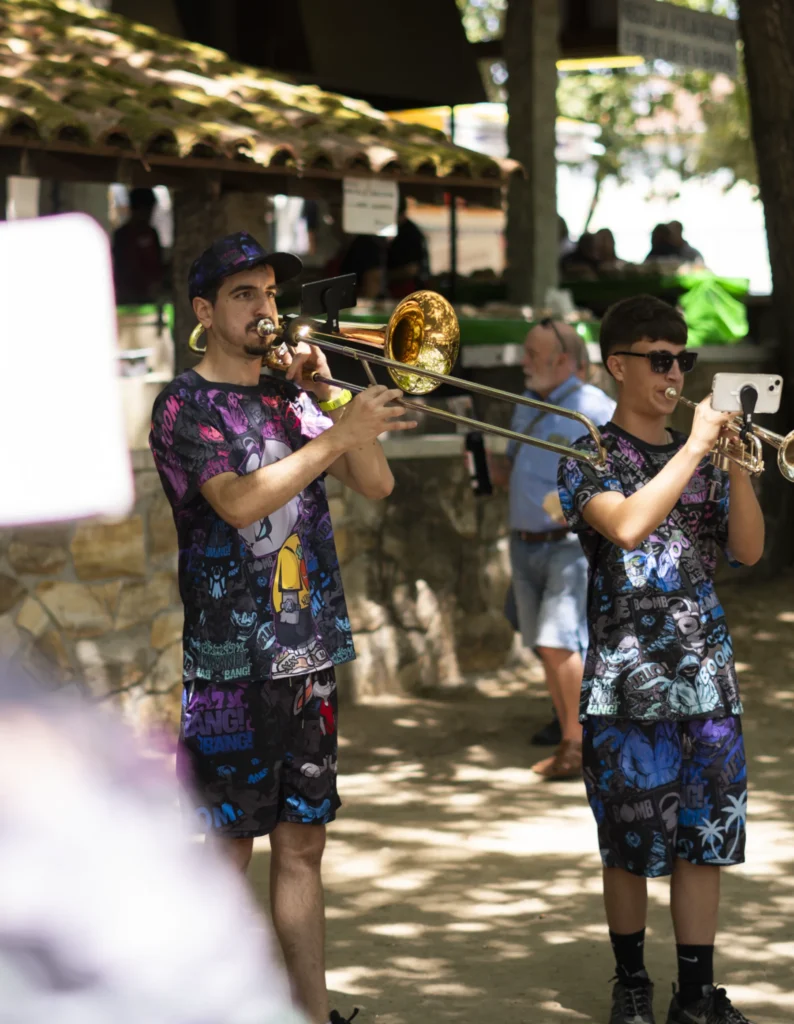 Trombonista e trompetista dunha charanga tocando baixo o soportal do recinto da festa