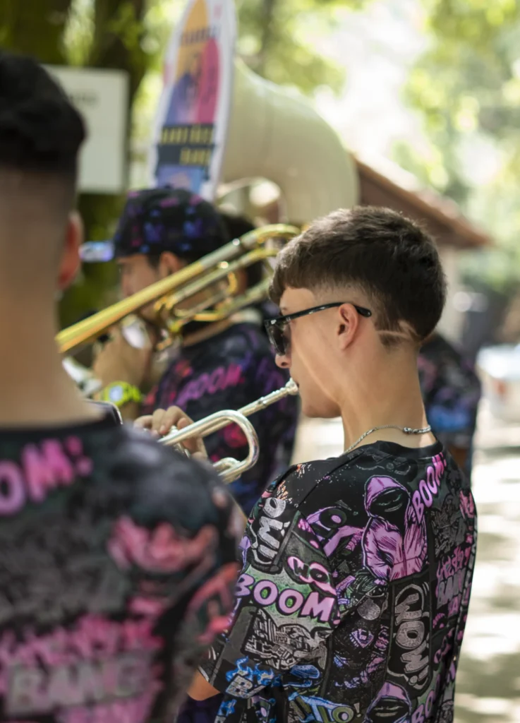 Trompetista novo da charanga tocando entre os seus compañeiros de camisola colorida