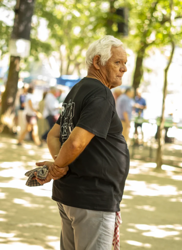 Veciño maior de pelo branco coa camisola da festa mirando o ambiente entre as árbores