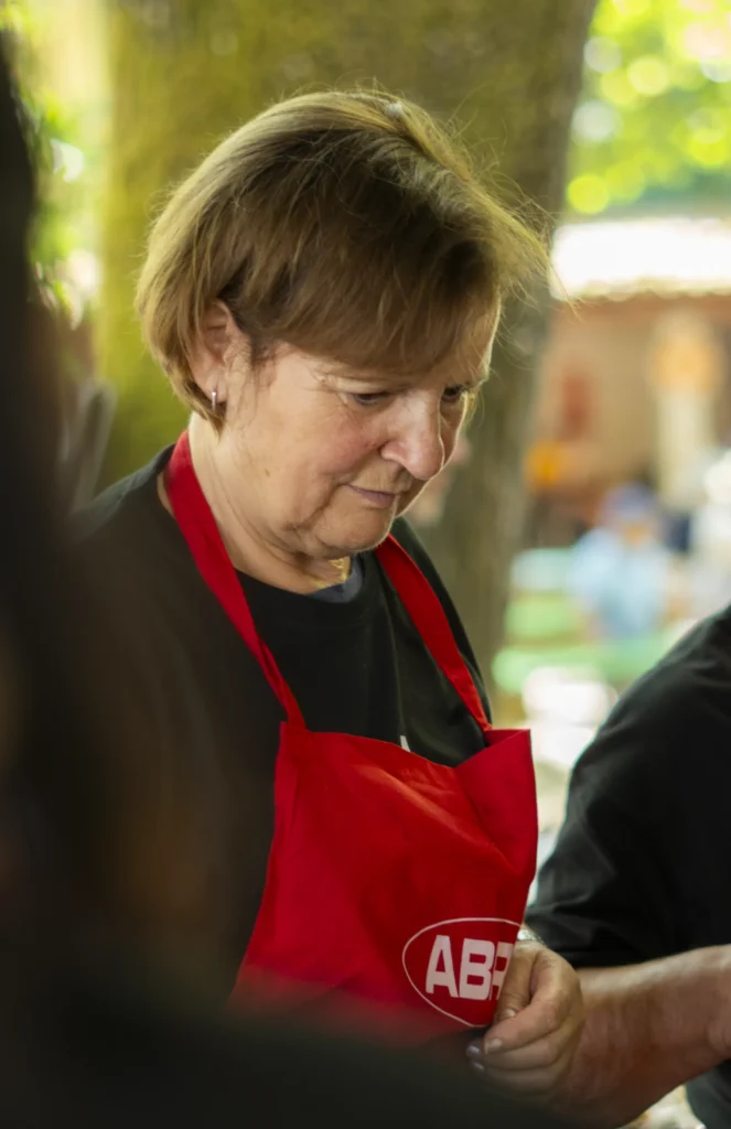 Voluntaria con mandil vermello prepara racións no posto de comida da carballeira