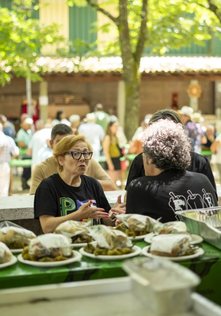Voluntarias conversando tras o mostrador con decenas de pratos de pementos xa preparados