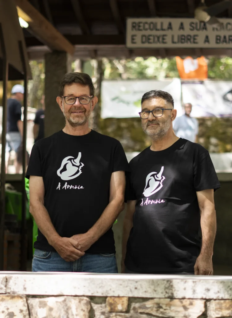 Dous voluntarios coa camiseta do pemento da Arnoia posan detrás da barra da festa